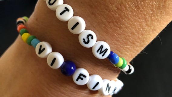 en del av en arm syns med två armband, med texten autism och vi finns.