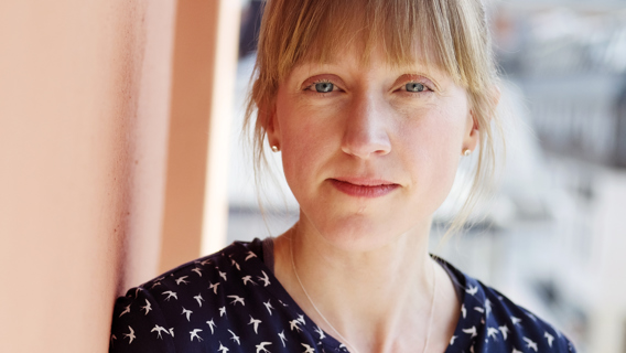 Porträttbild på Lina Liman som lutar sig mot en vägg. 