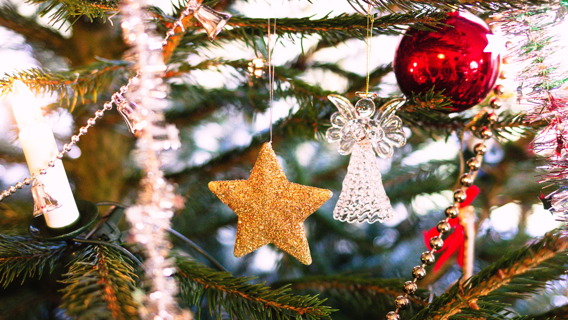 Guldstjärna, ängel, röd kula och glitter bland grangrenar