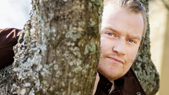 Alexander Skytte tittar fram emellan två träd. 